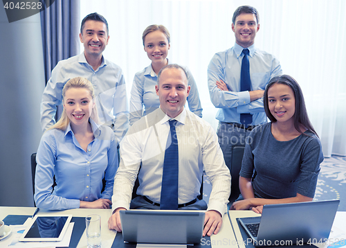 Image of smiling business people with laptop in office