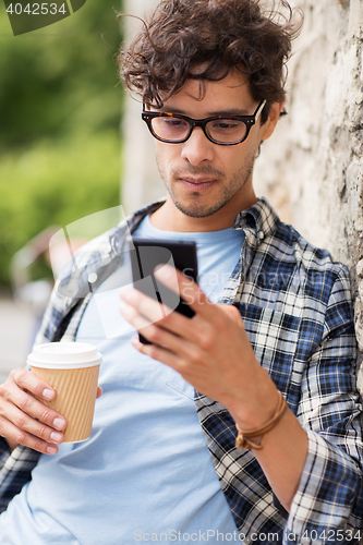 Image of man with smartphone drinking coffee on city street