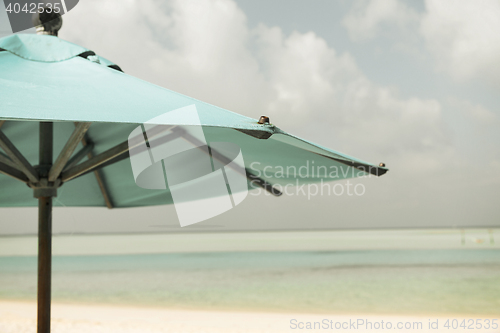 Image of parasol over blue sky and beach