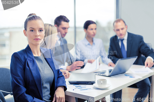 Image of businesswoman in office with team on the back