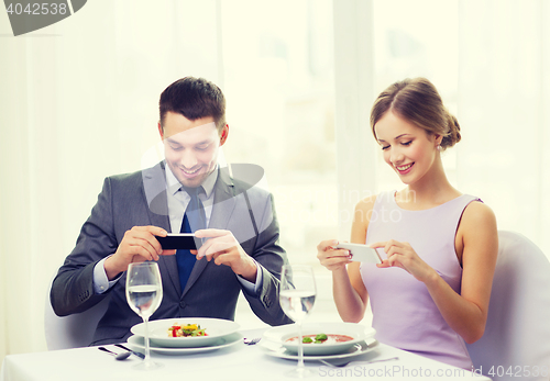 Image of smiling couple with appetizers and smartphones