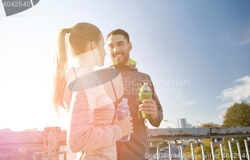 Image of smiling couple with bottles of water outdoors