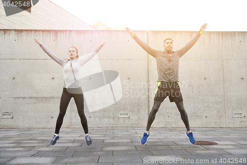 Image of happy man and woman jumping outdoors