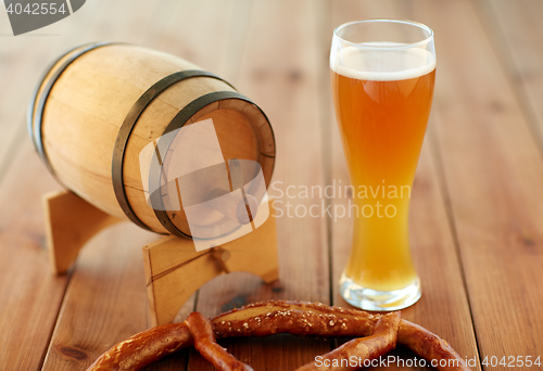 Image of close up of beer glass, pretzel and wooden barrel