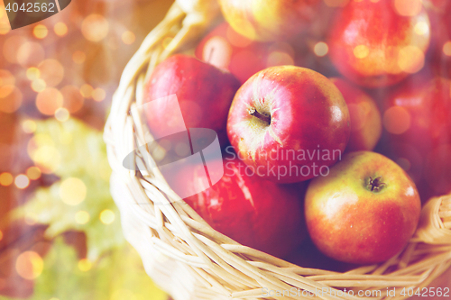 Image of close up of basket with apples on wooden table