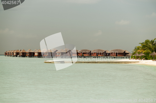 Image of bungalow huts in sea water on exotic resort beach