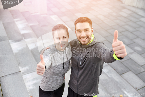 Image of smiling couple showing thumbs up on city street