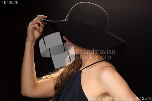 Image of beautiful woman in black hat over dark background