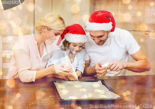 Image of happy family in santa helper hats making cookies