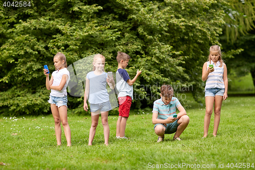 Image of kids with smartphones playing game in summer park