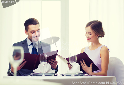 Image of smiling couple with menus at restaurant