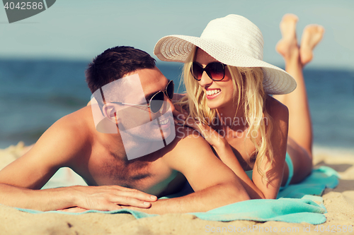 Image of happy couple in swimwear lying on summer beach