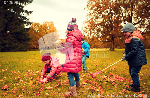 Image of group of children collecting leaves in autumn park