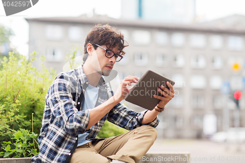 Image of man with tablet pc sitting on city street bench