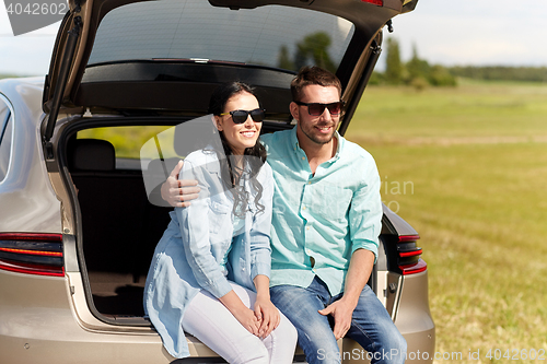 Image of happy couple hugging at open hatchback car trunk