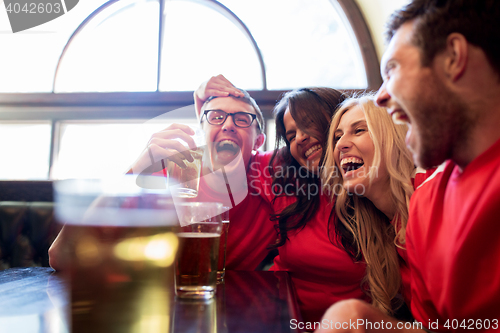 Image of football fans or friends with beer at sport bar