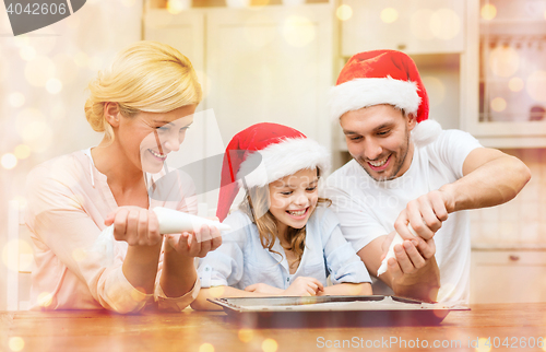 Image of happy family in santa helper hats making cookies