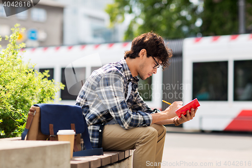 Image of man with notebook or diary writing on city street