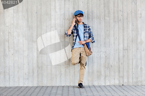 Image of man with bag calling on smartphone at street wall