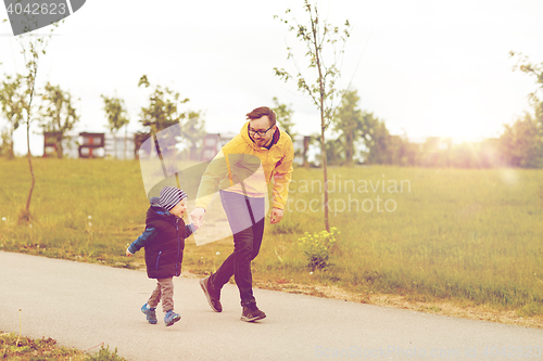 Image of happy father and little son walking outdoors