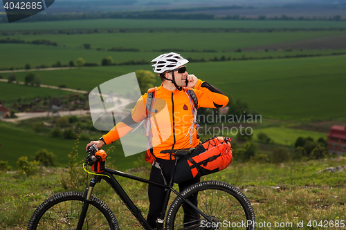 Image of Young man standing near the cycle on a green meadow