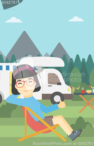 Image of Woman sitting in chair in front of camper van.