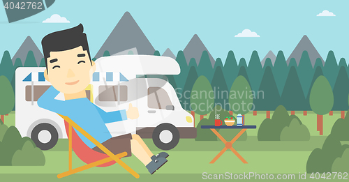 Image of Man sitting in chair in front of camper van.