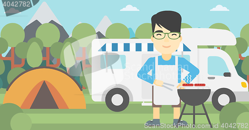Image of Man having barbecue in front of camper van.