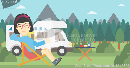 Image of Woman sitting in chair in front of camper van.