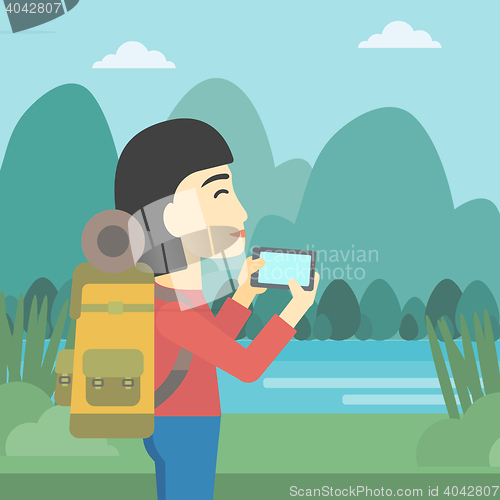 Image of Woman with backpack taking photo.