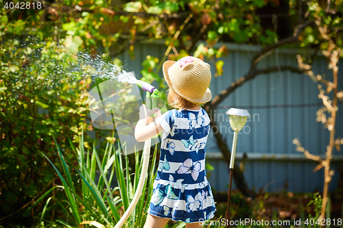 Image of Little happy girl watering garden