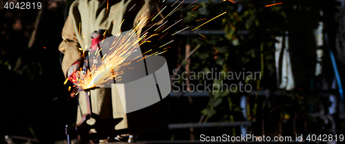 Image of Worker cutting metal with grinder. Sparks while grinding iron