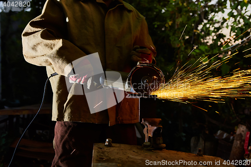 Image of Worker cutting metal with grinder. Sparks while grinding iron