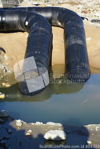 Image of two balck metal pipes going into the river