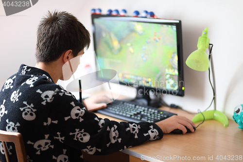 Image of Boy using computer at home, playing game