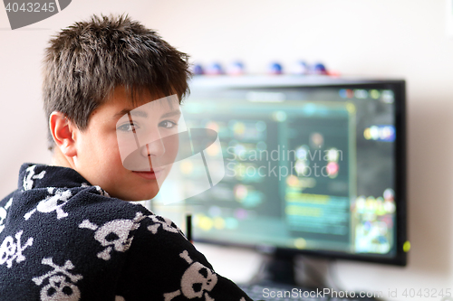 Image of Boy using computer at home, playing game