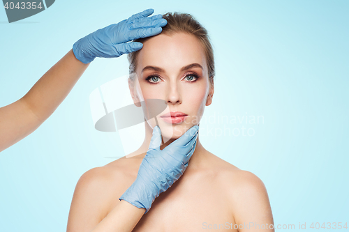 Image of surgeon or beautician hands touching woman face