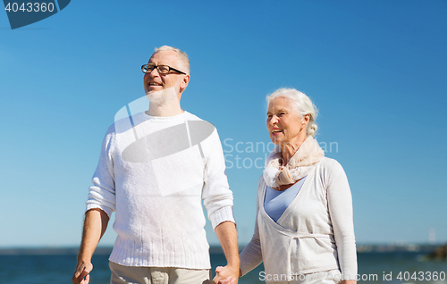 Image of happy senior couple holding hands on summer beach