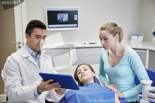 Image of dentist showing tablet pc to girl and her mother