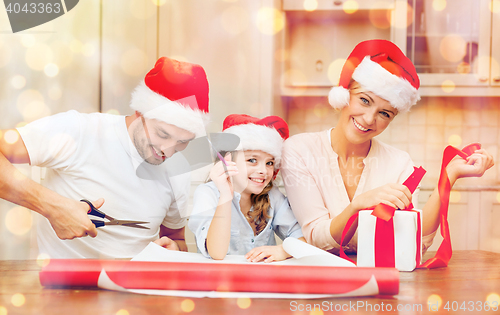 Image of smiling family in santa helper hats with gift box