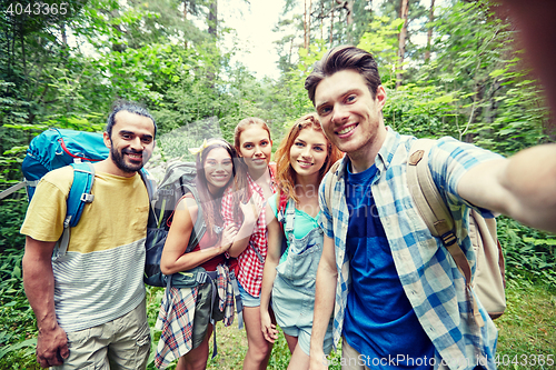 Image of friends with backpack taking selfie in wood