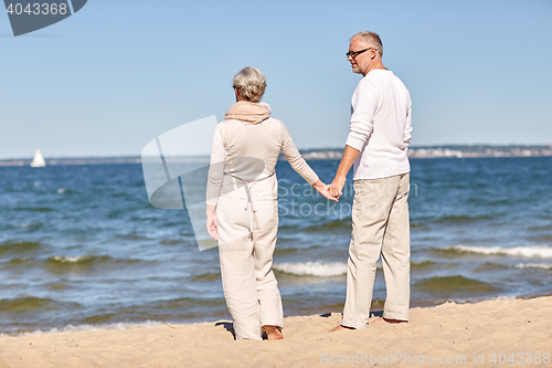 Image of happy senior couple holding hands summer beach