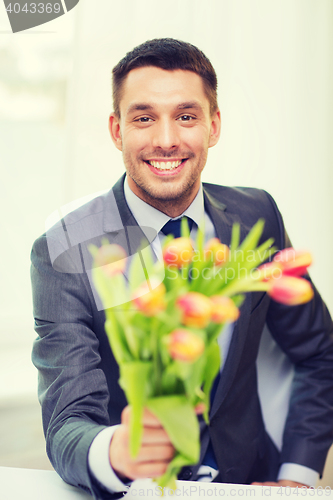 Image of smiling handsome man giving bouquet of flowers