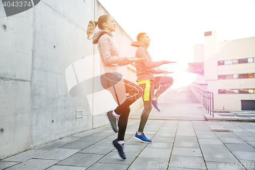 Image of happy man and woman jumping outdoors