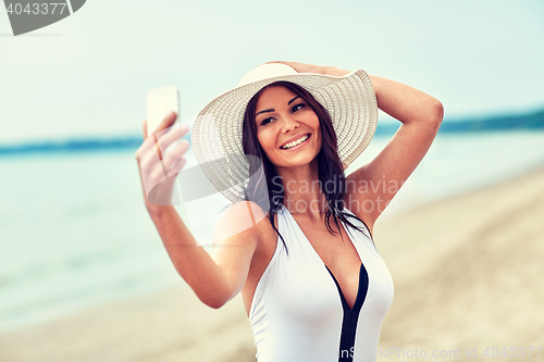 Image of smiling young woman taking selfie with smartphone