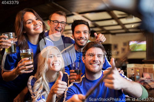 Image of football fans with beer taking selfie at pub