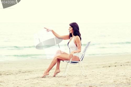 Image of smiling young woman sunbathing in lounge on beach