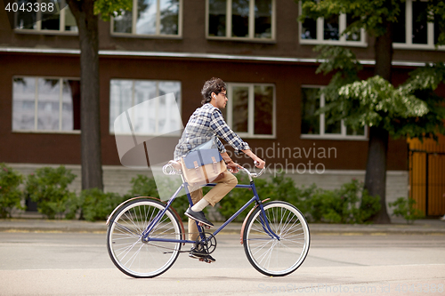 Image of young hipster man with bag riding fixed gear bike