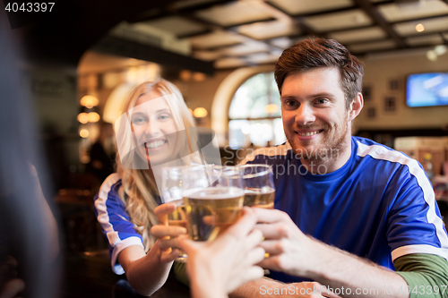Image of football fans clinking beer glasses at sport bar