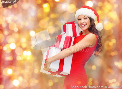 Image of smiling woman in santa hat holding gift boxes